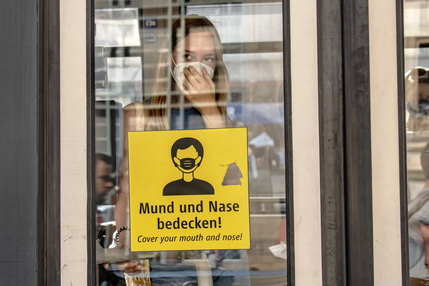 Naine trammis, mille uksel on maskikandmise kohustusele osundav silt, Münchenis 13. augustil 2022. a.
