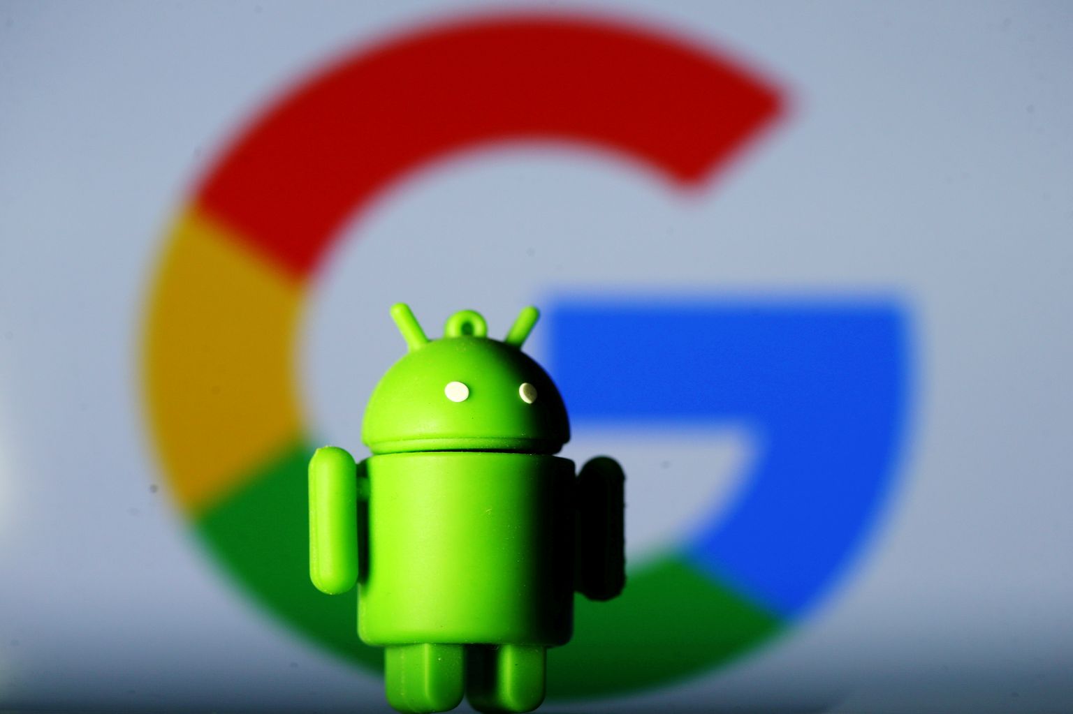 Androidi maskott Google'i logo taustal.