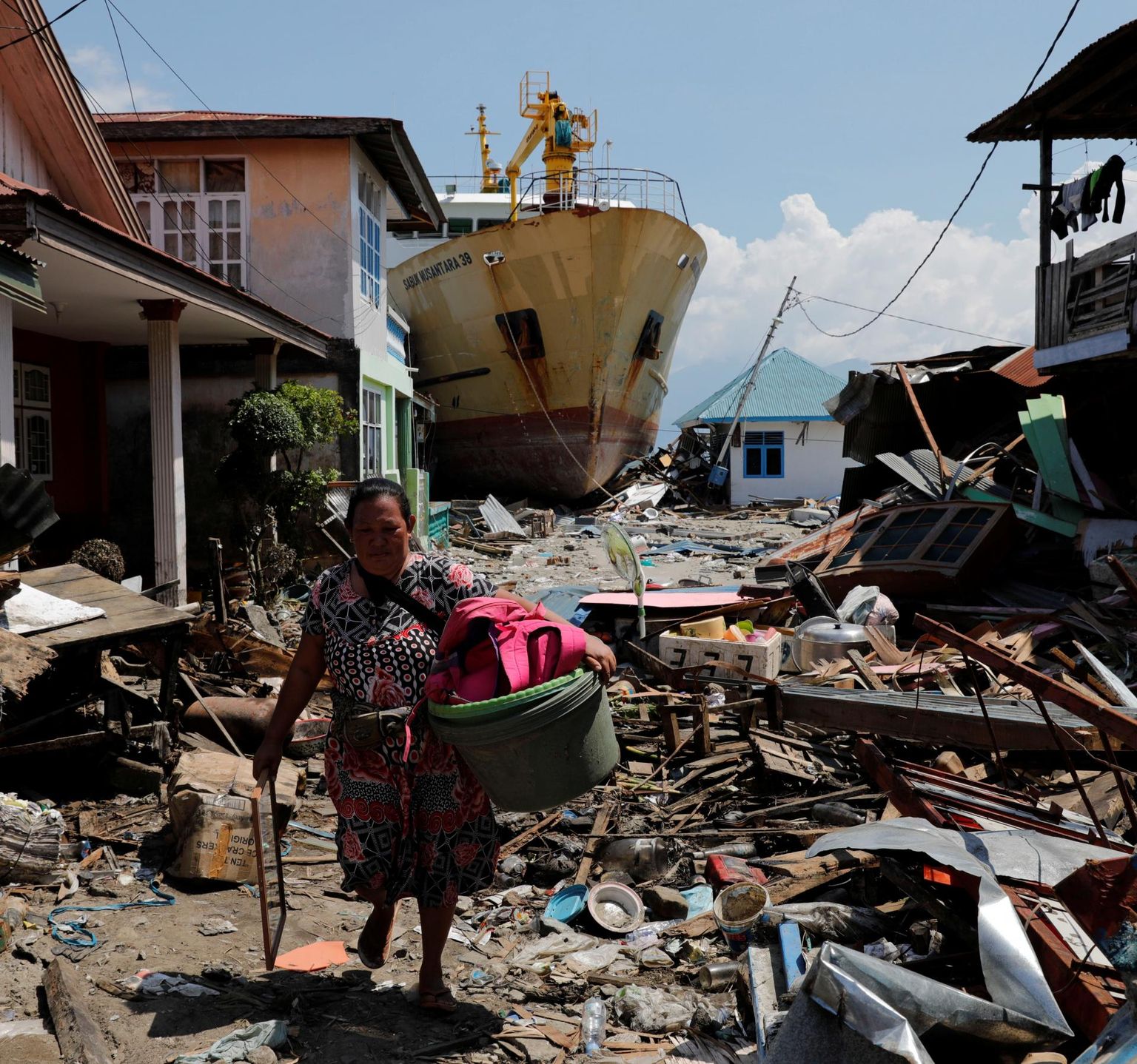 Naine kõndimas oma varanatukesega tsunamis kannatada saanud Wani külas Donggala regioonis. Seni pole päästjad ja toiduabi piirkonda õieti jõudnud.