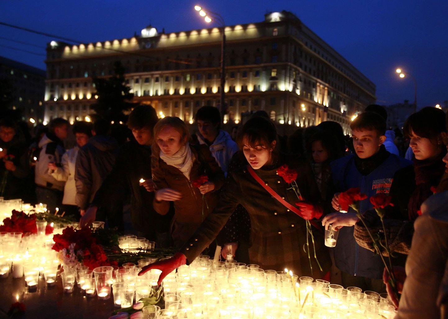 Inimesed asetavad küünlaid ja lilli Lubjanka metroojaamas hukkunute mälestuseks, Tagaplaanil paistab FSB peahoone.