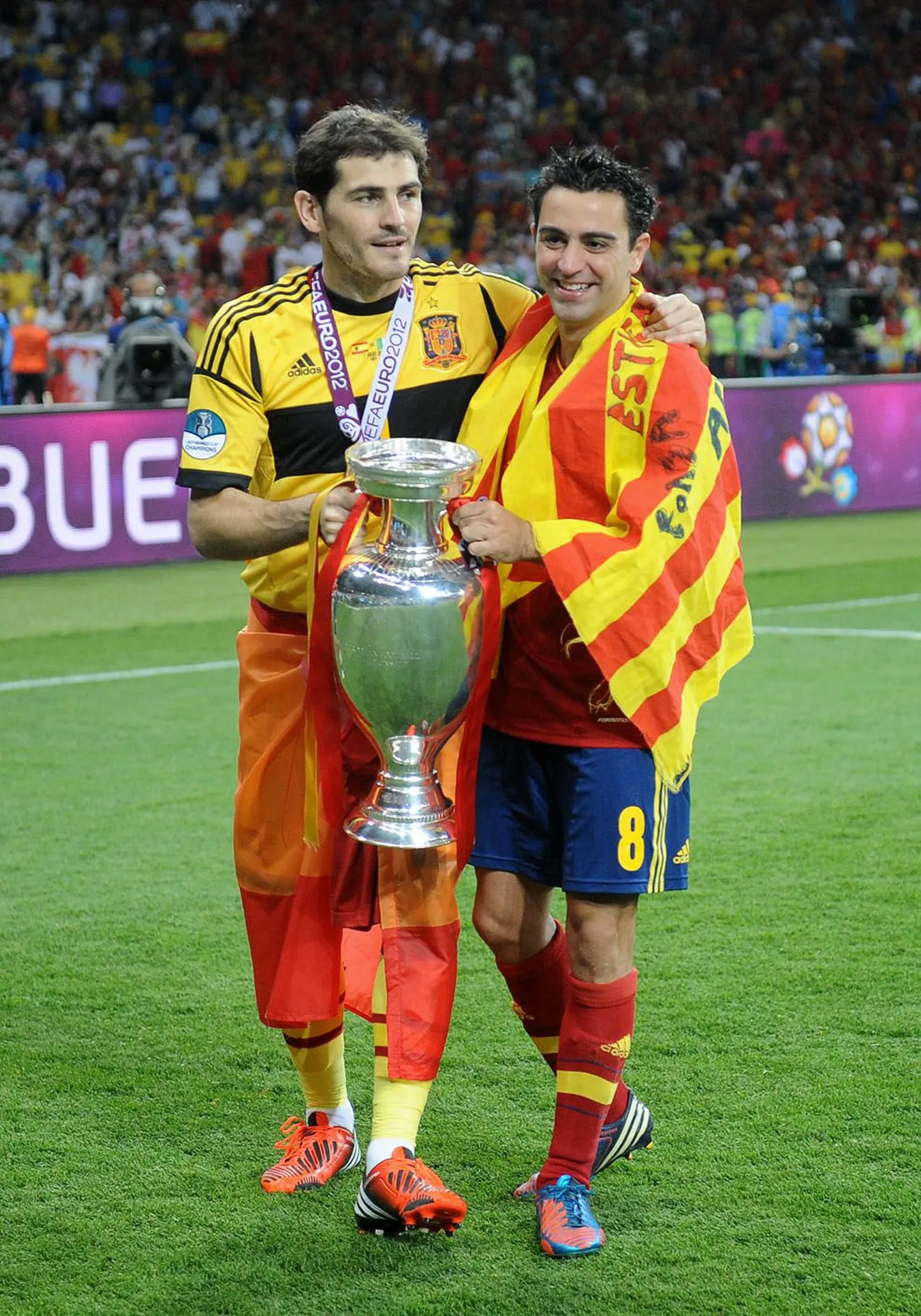 Madridi Reali kapten Iker Casillas (vasakul) ja FC Barcelonas Carles Puyolilt selle ameti üle võtnud Xavi tähistamas Hispaania koondise viimast suurt triumfi ehk 2012. aasta EM-tiitlit.