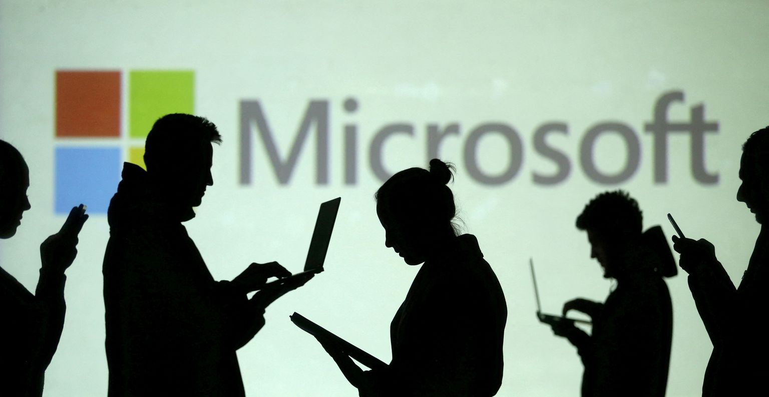 FILE PHOTO: Silhouettes of laptop and mobile device users are seen next to a screen projection of Microsoft logo in this picture illustration taken March 28, 2018.  REUTERS/Dado Ruvic/Illustration/File Photo