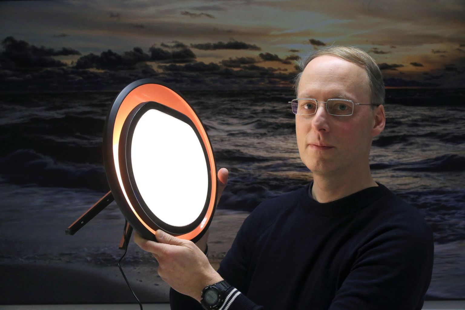 Genoomika ja metaboloomika kaasprofessor Toomas Haller näitab uuringulampi, taustal Indrek Kase foto hetkest, mil päike on silmapiiri taha vajunud ning pimedus laskunud maale ja merele.