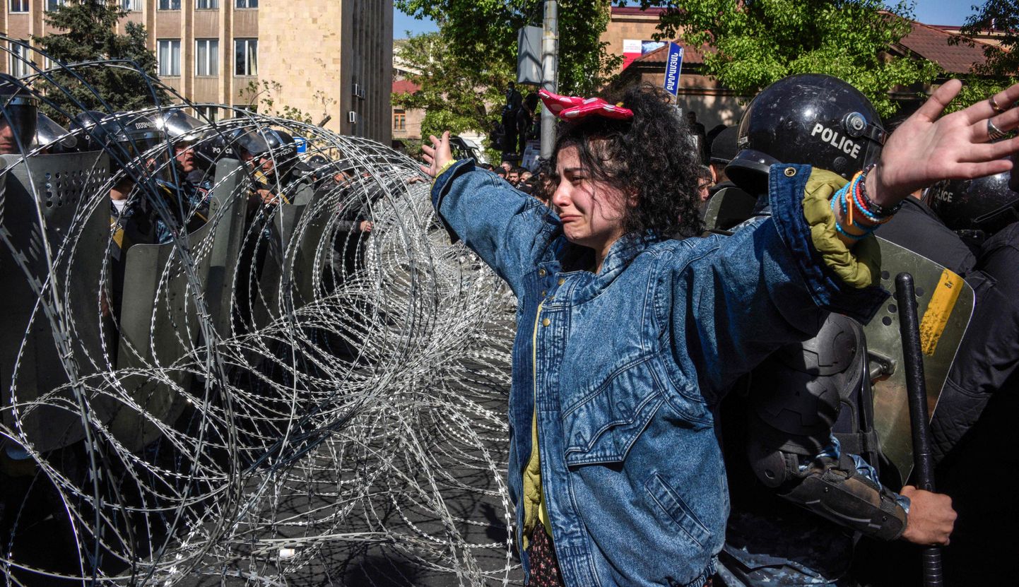Opositsiooniline meelevaldaja rahu märgiks üles tõstetud kätega politsei okastraataia juures.