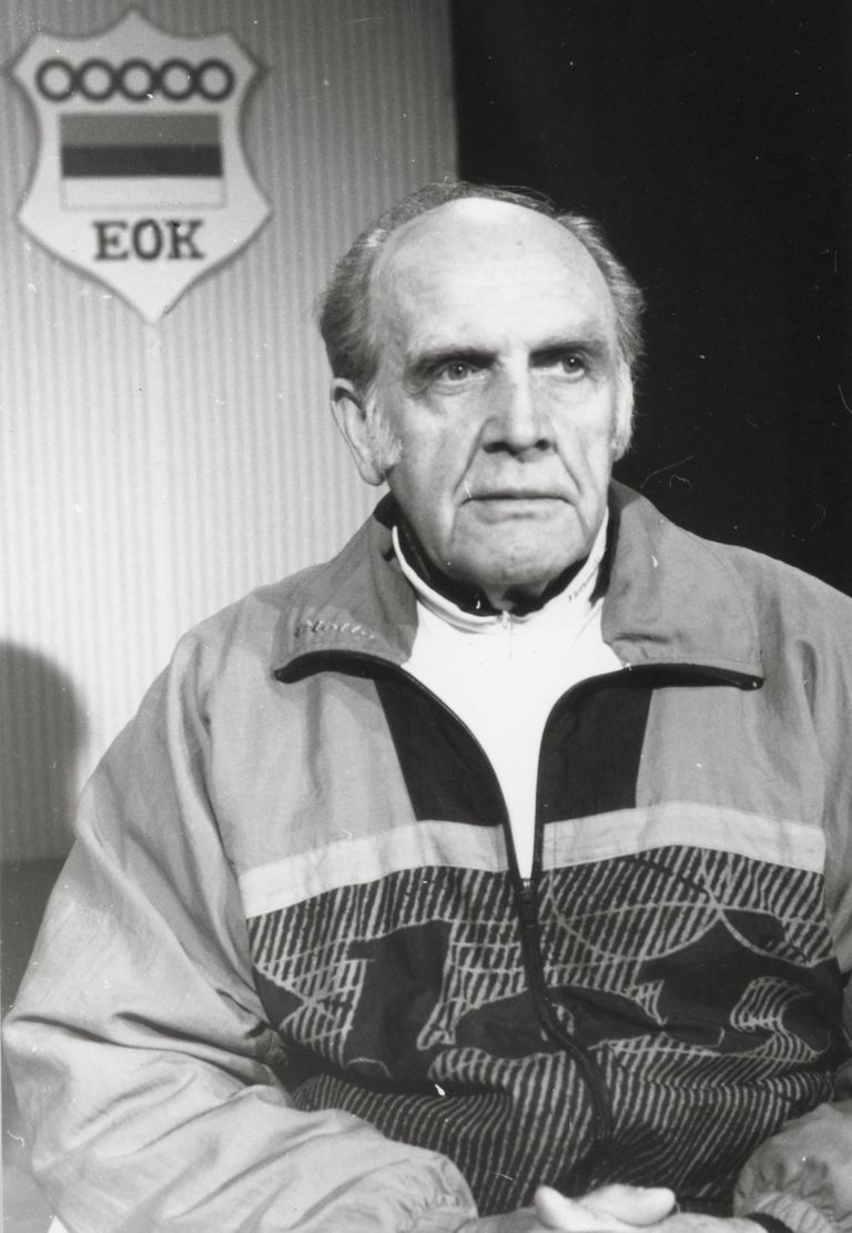 Eesti Olümpiakomitee president Arnold Green (u 1990). Tema selja taga on näha sümboolikat, mida EOK kasutas kuni Rahvusvahelise Olümpiakomitee ametliku tunnustuse saamiseni – ebatraditsiooniliselt üksteise kõrval olevaid rõngaid.