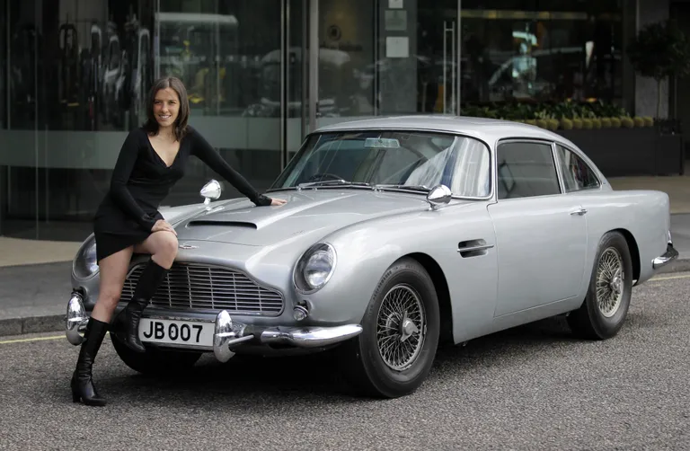 Sieviete pozē pie oriģinālā Džeimsa Bonda Aston Martin DB5