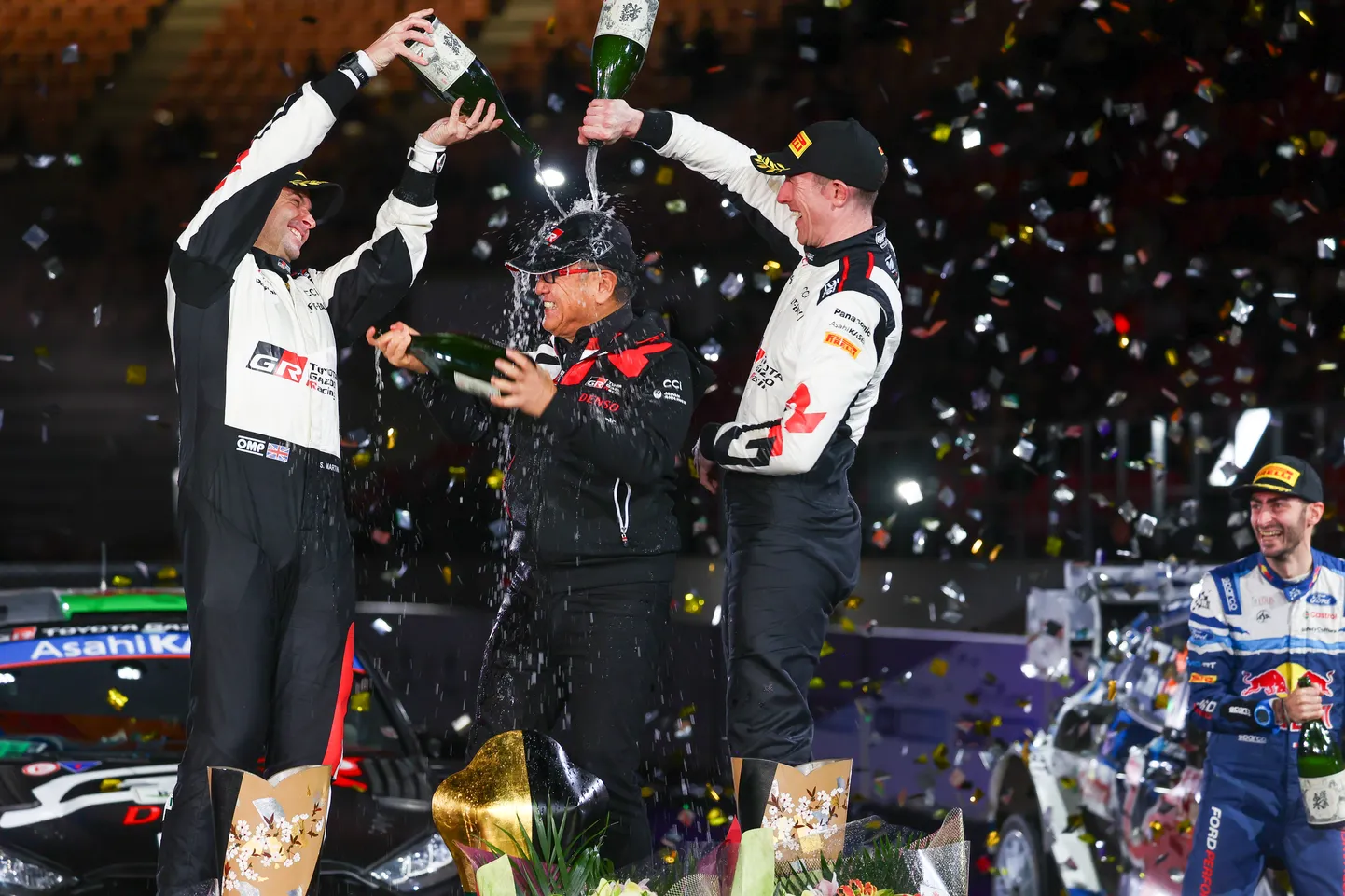 Toyota juhatuse esimees Akio Toyoda (keskel) ja Jaapani ralli võitjad Elfyn Evans (paremal) ja kaardilugeja Scott Martin poodiumil.
