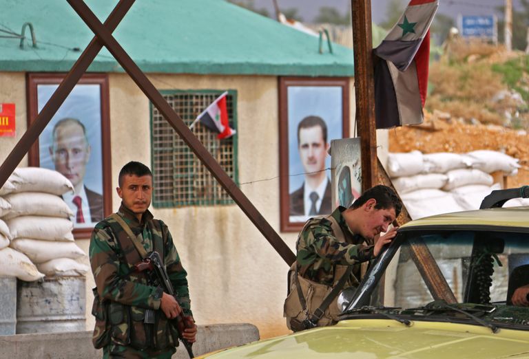 Süüria valitsusvägede liikmed kontrollpunktis. Taustal Vladimir Putini ja Bashar al-Assadi pildid.