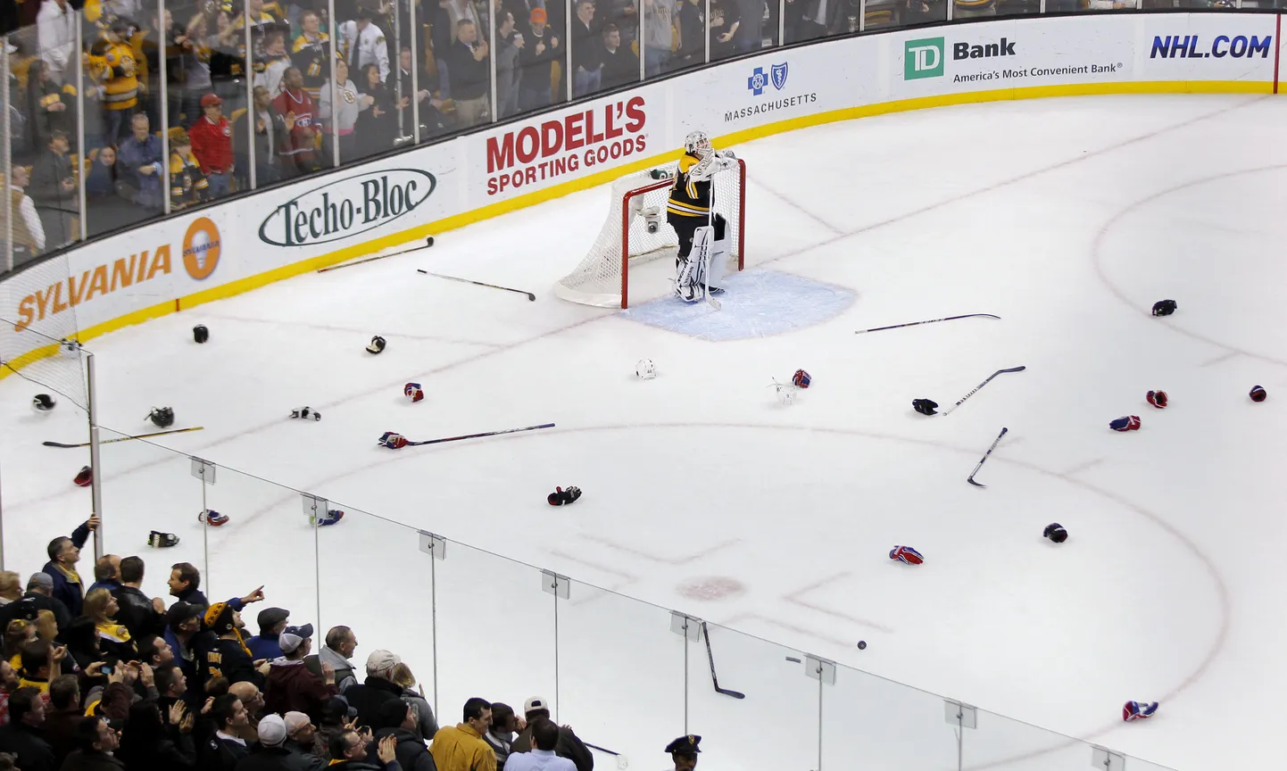 Boston Bruinsi väravavaht Tim Thomas seisab väravasuul, ümbritsetud madina järel jääle jäänud hokikeppidest ja kinnastest.