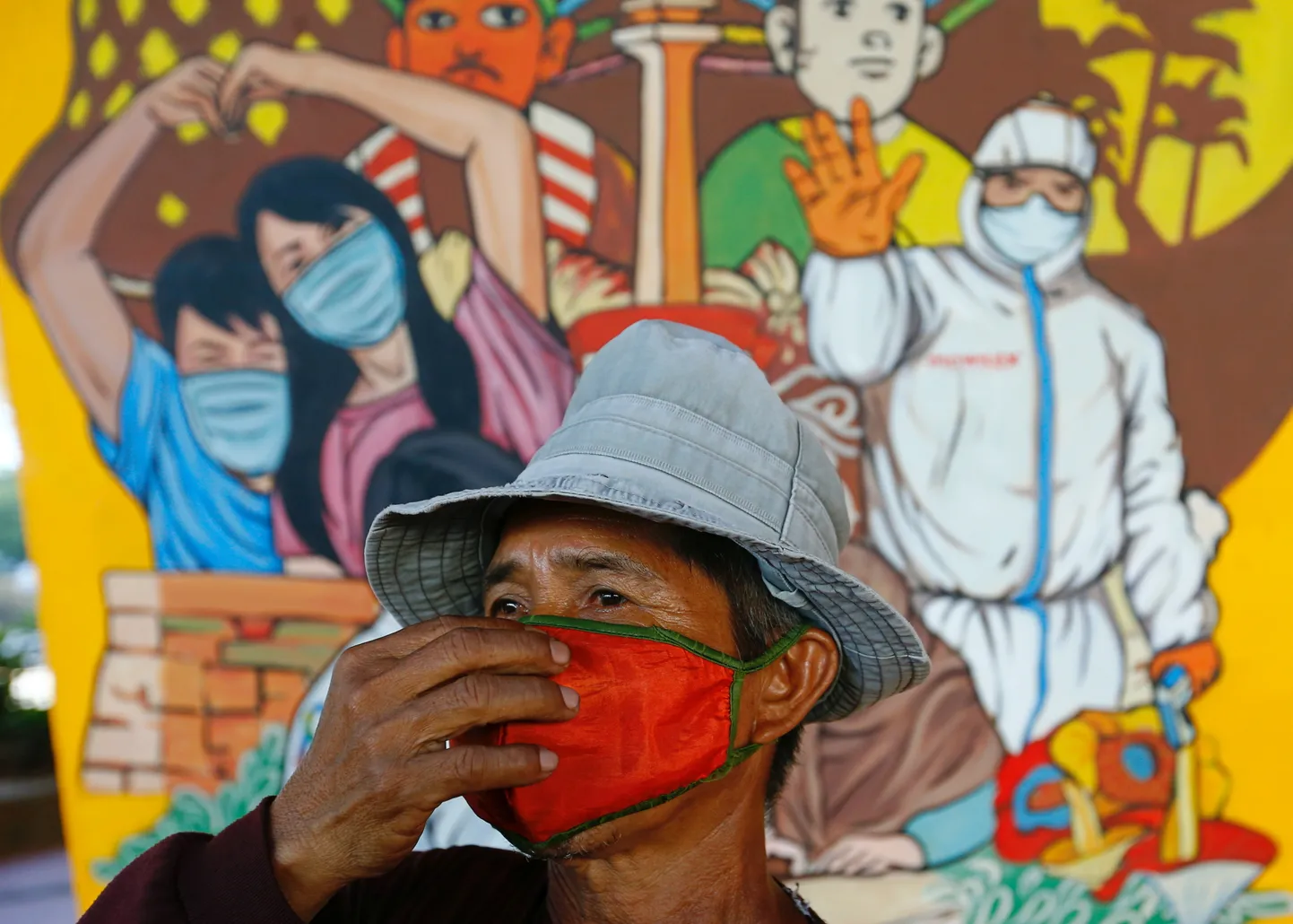 Mees jalutamas mööda COVID-19 teemalisest seinamaalingust Jakartas.