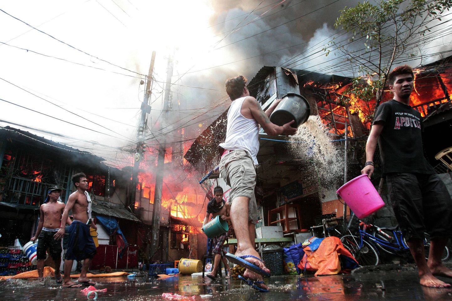 Kohalikud elanikud püüavad kustutada Manila slummis puhkenud tulekahju.