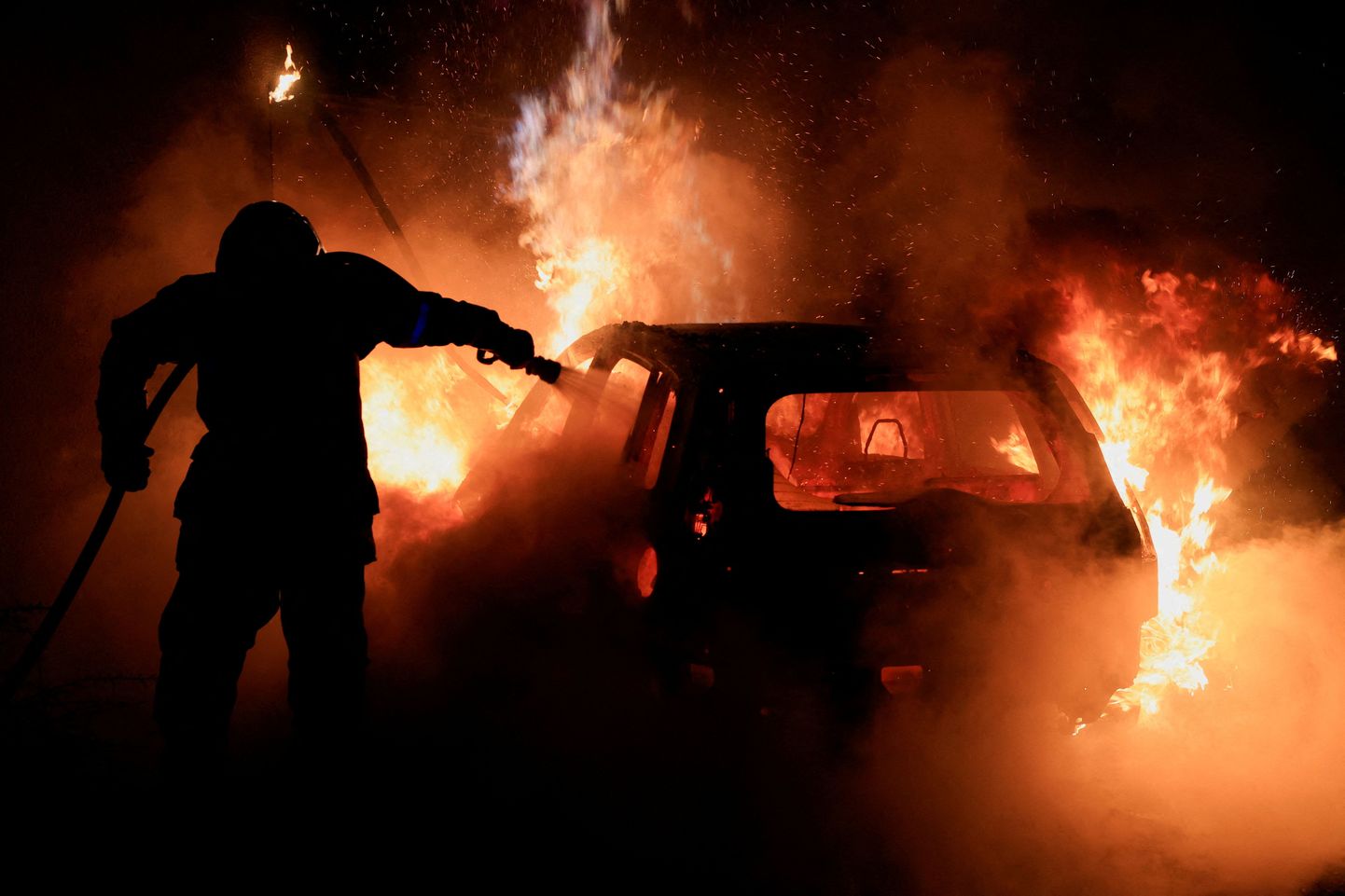 Prantsuse tuletõrjuja kustutamas rüüstamise käigus süüdatud autot.