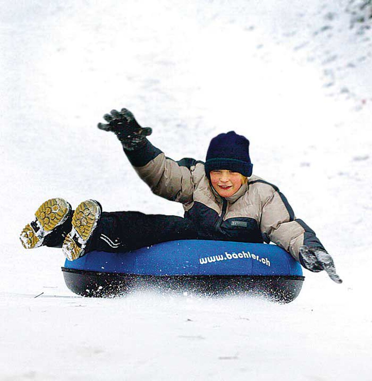 Laps snowtube rõngaga mäest alla sõitmas.