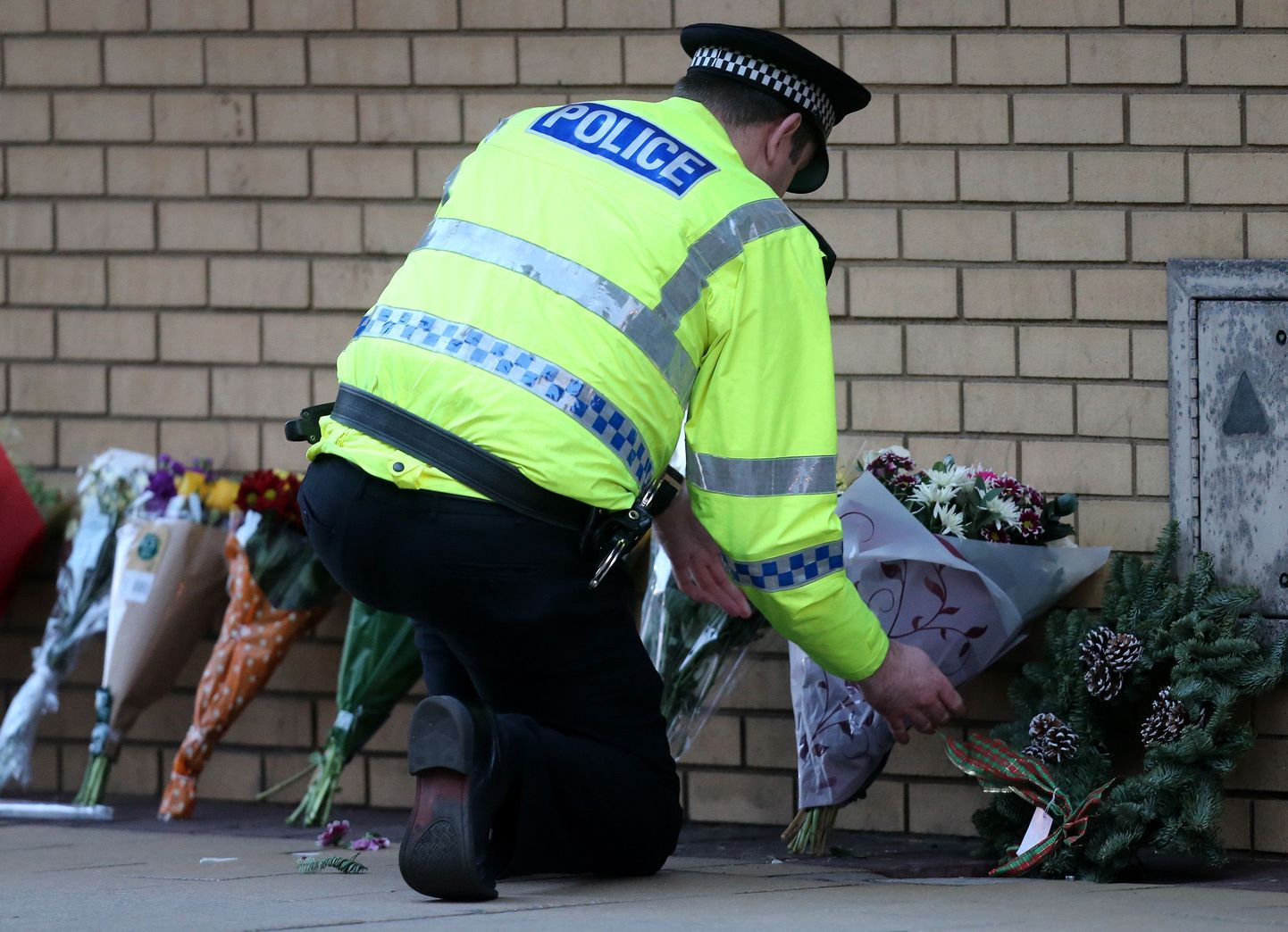 Politseinik asetab kopterõnnetuse ohvrite mälestuseks lilli Glasgow pubi The  Clutha lähistele.