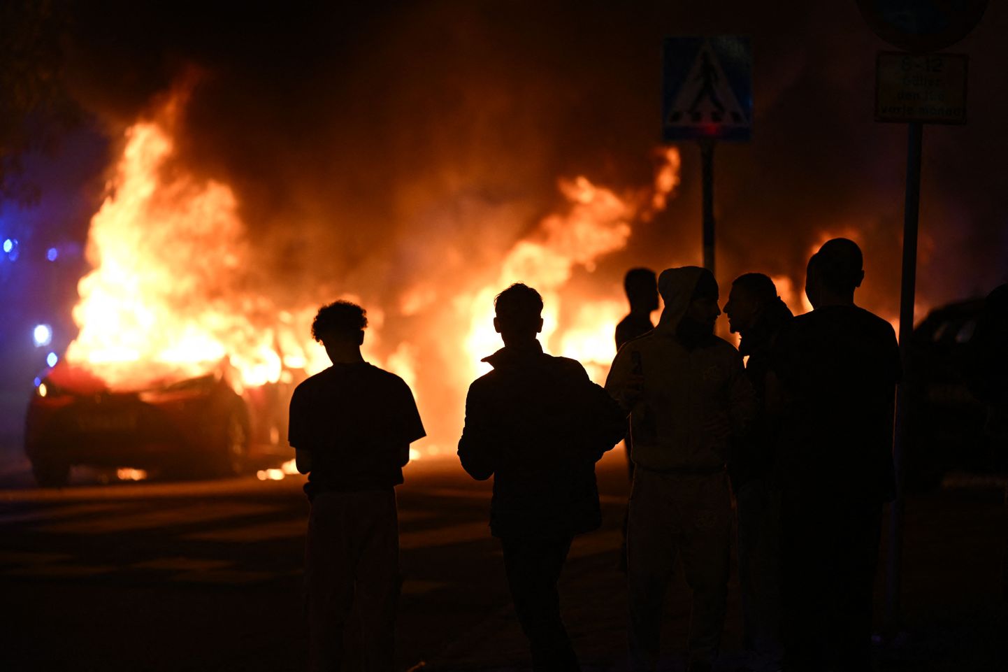 Inimesed vaatavad põlevaid autosid Malmös Rosengårdi linnaosas eelmise aasta septembris, kui piirkonnas vallandusid pärast koraani põletamist rahutused.