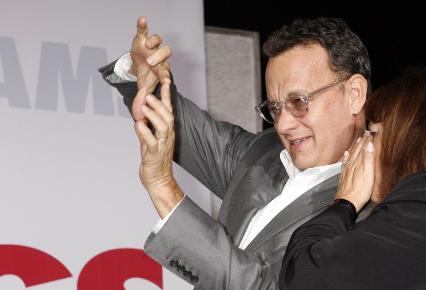 Actor Tom Hanks uses his fingers as a "view finder" as he watches his wife Rita Wilson pose at the premiere of her new film "Old Dogs" in Hollywood, California November 9, 2009. Rita Wilson's publicist Heidi Schaeffer is shown (R.)  REUTERS/Fred Prouser    (UNITED STATES ENTERTAINMENT)
