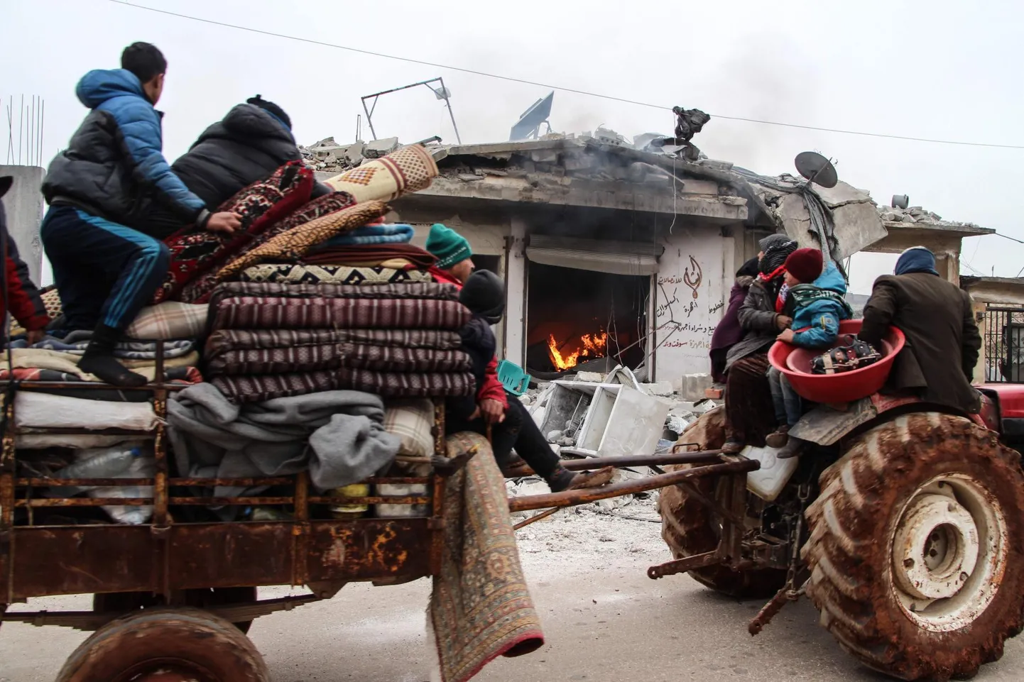 Valitsusvägede rünnakute eest põgenev Süüria perekond möödumas põlevast kauplusehoonest Abin Semaanis Aleppost läänes. 