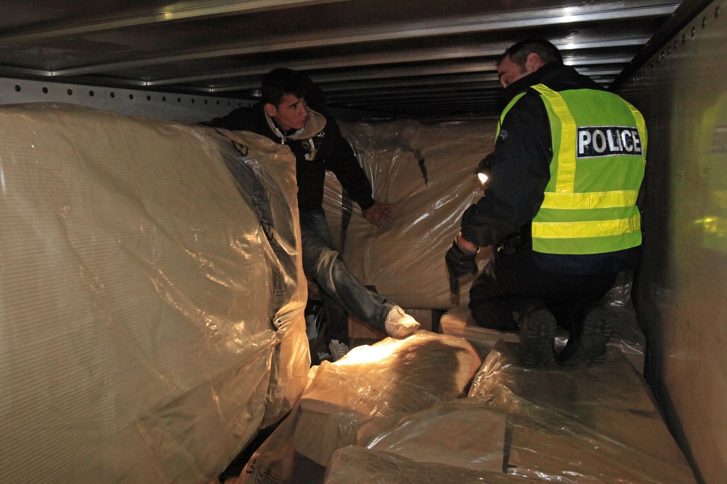 Prantsuse politseinik Calais' sadamas veoki kastist tabatud afgaaniga.