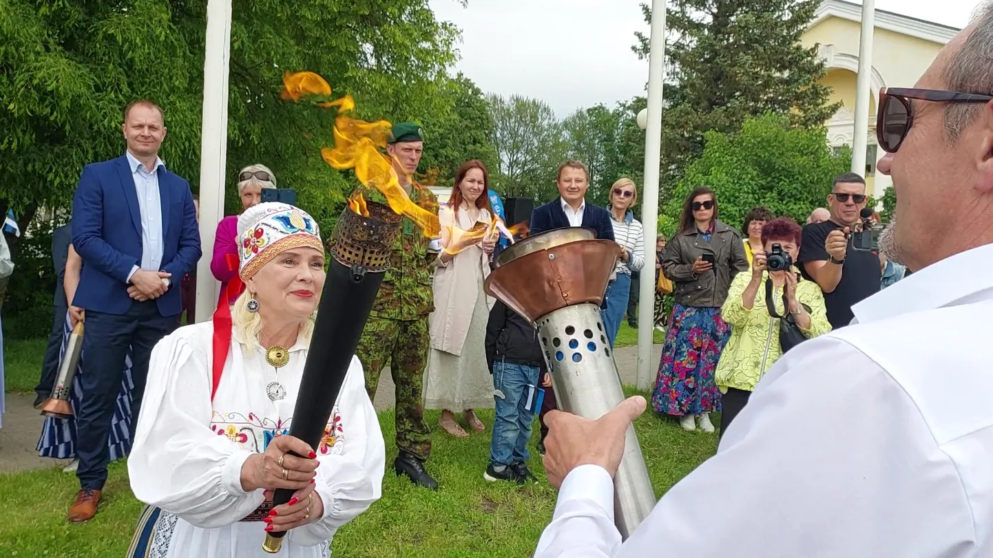 Ida-Virumaa Omavalitsuste Liidu esimees Eve East jagas võidupüha pärastlõunal Sillamäe keskväljakul võidutuld Ida-Virumaa omavalitsusjuhtidele, et need viiksid selle jaanitulede süütamiseks oma linnades ja valdades. Pildil võtab tule vastu Sillamäe linnavolikogu esimees Valeri Abramovitš.