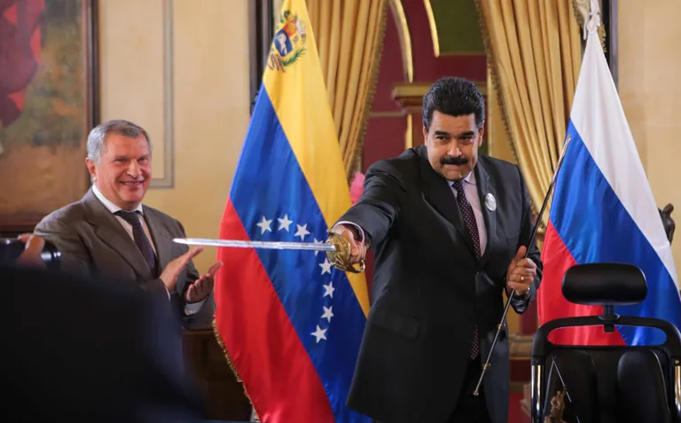 Президент Венесуэлы Николас Мадуро (справа) держит копию меча национального героя Венесуэлы Симона Боливара, а глава «Роснефти» Игорь Сечин (слева) радуется, наблюдая за своим другом во время подписания соглашения между «Роснефтью» и венесуэльской нефтяной компанией PDVSA в Каракасе, Венесуэла, 28 июля 2016 года.
