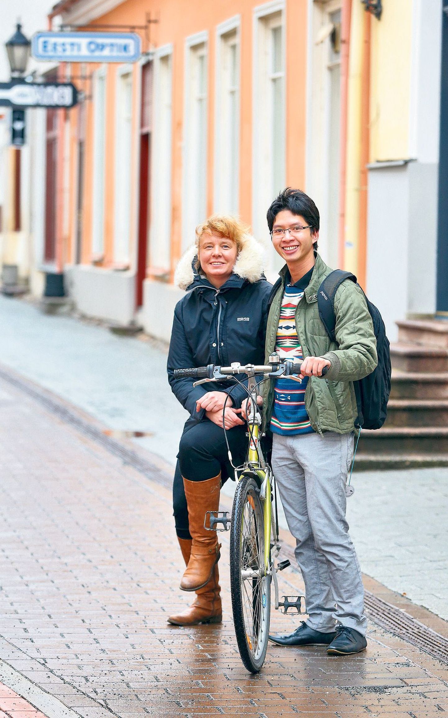 Thai Van Nguyen jalgrattaga Rüütli tänaval, pakiraamil doktoritöö juhendaja, Tartu ülikooli ortodont Triin Jagomägi.