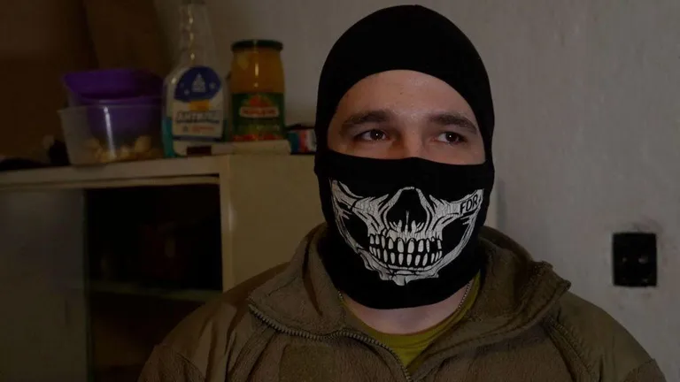 Сурт скрывает свое лицо балаклавой.