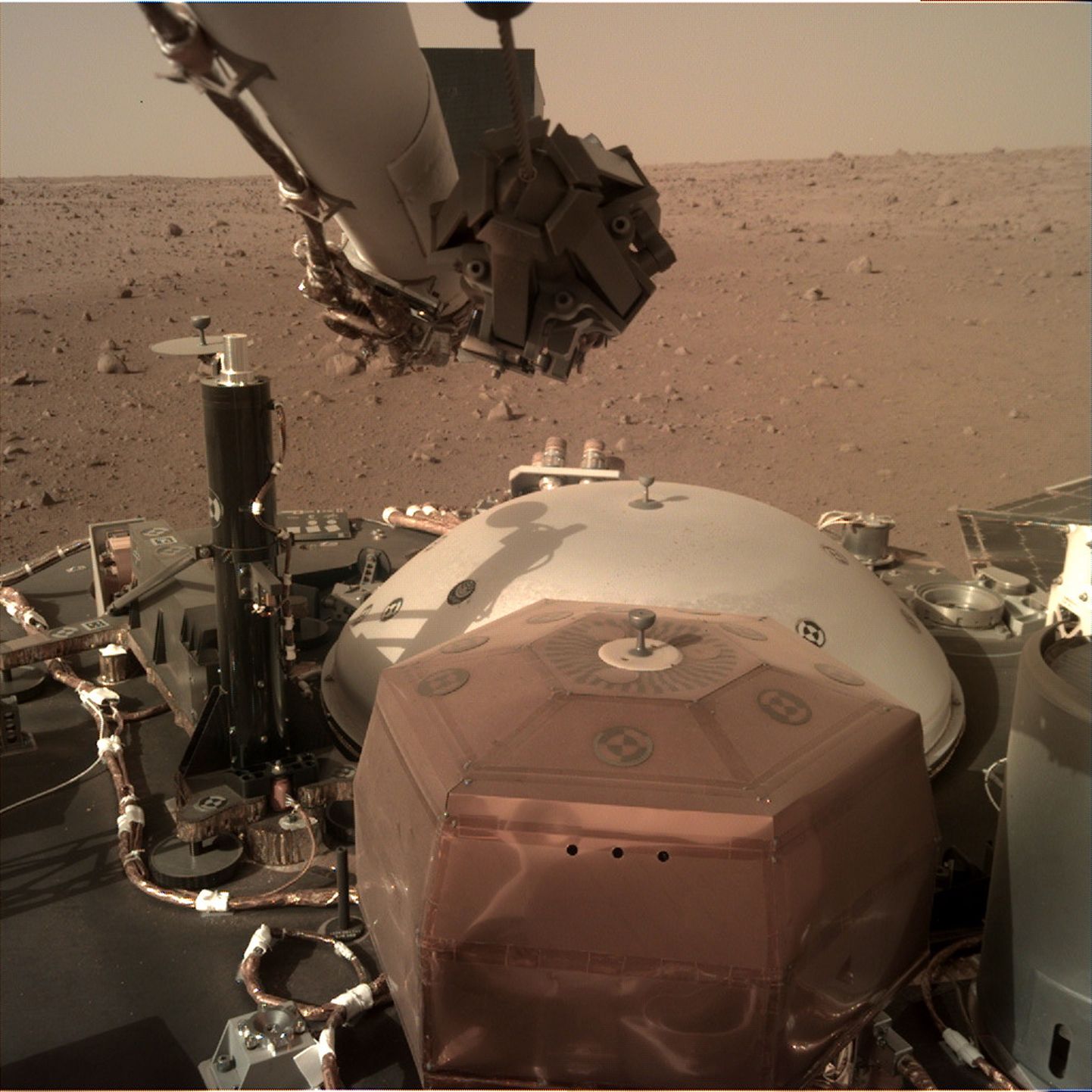 NASA fotol on näha InSight maandurit asetamas Marsi pinnale seismomeetrit.