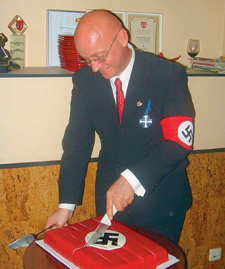 Надевший повязку со свастикой и Крест Маарьямаа Ристо Тейнонен режет торт с изображением свастики в годовщину конференции в Ванзе, посвященной убийству евреев.