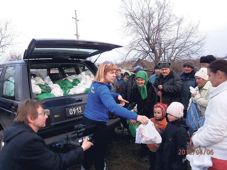 Inna Šulženko jagab 6. aprillil 2015. aastal Luganski oblasti ühes külakeses toidupakke. Vasakul filmib Vahur Laiapea.