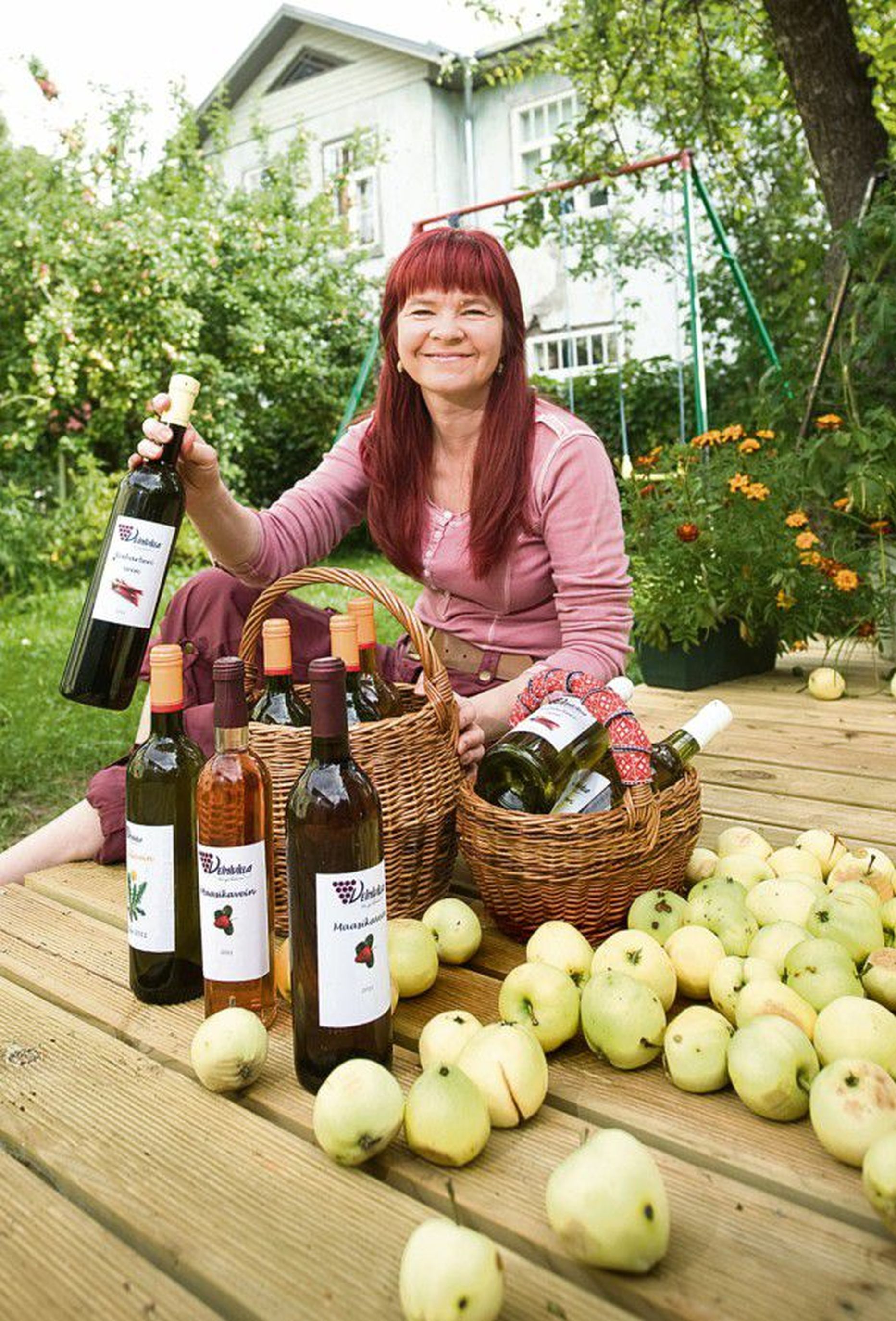 Rõõmustab veinisaagi üle: Tiina Kuuler näitab koduõuel valikut sel suvel pudelisse pandud     veinidest – võilillest, maasikast, rabarberist.