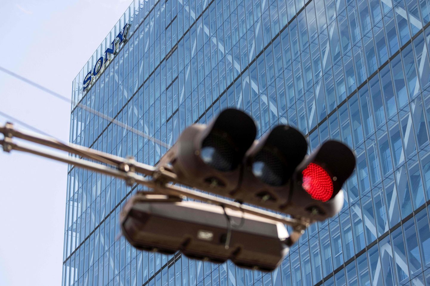 A traffic red light is photographed in front of the logo of Japanese tech giant Sony on the company's headquarters building in Tokyo on February 2, 2022. (Photo by Behrouz MEHRI / AFP)