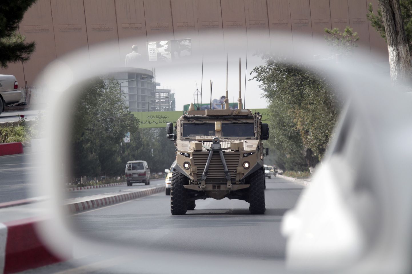 A patrolling U.S. armored vehicle is reflected in the mirror of a car in Kabul, Afghanistan, Wednesday, Aug. 23, 2017.  In a national address Monday night, U.S. President Donald Trump reversed his past calls for a speedy exit and recommitted the United States to the 16-year-old conflict, saying U.S. troops must "fight to win." (AP Photo/Rahmat Gul)