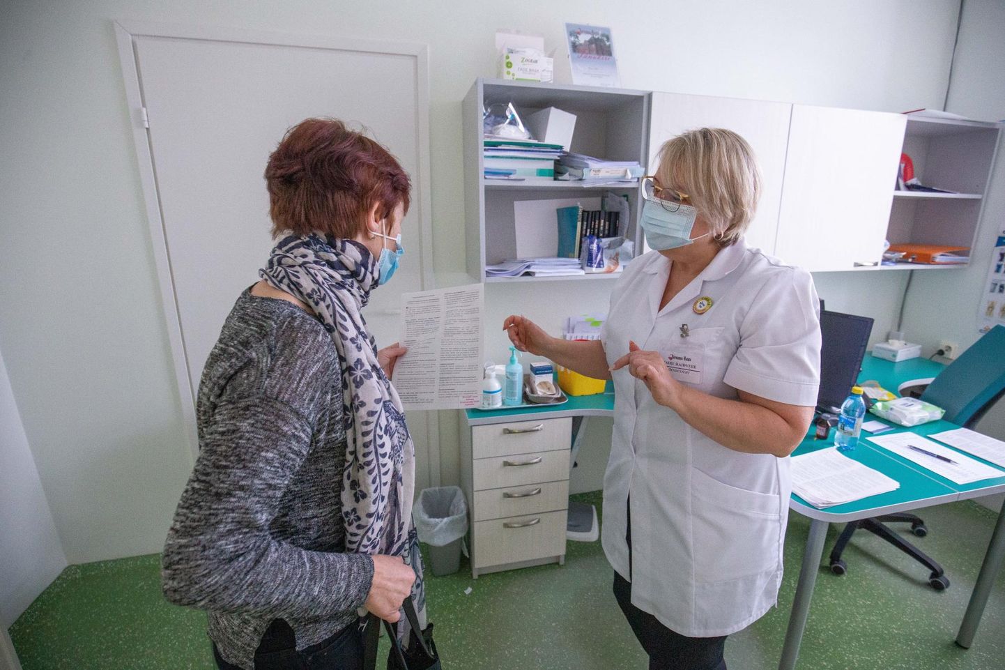 Kaks nädalat tagasi vaktsineeriti Järvamaa haiglas 100 eakat. Haigla õendusjuht Maire Raidvere ulatab vakstiini saanud patsiendile teabelehe, kus on kirjas, mida vaktsiin endast kujutab.