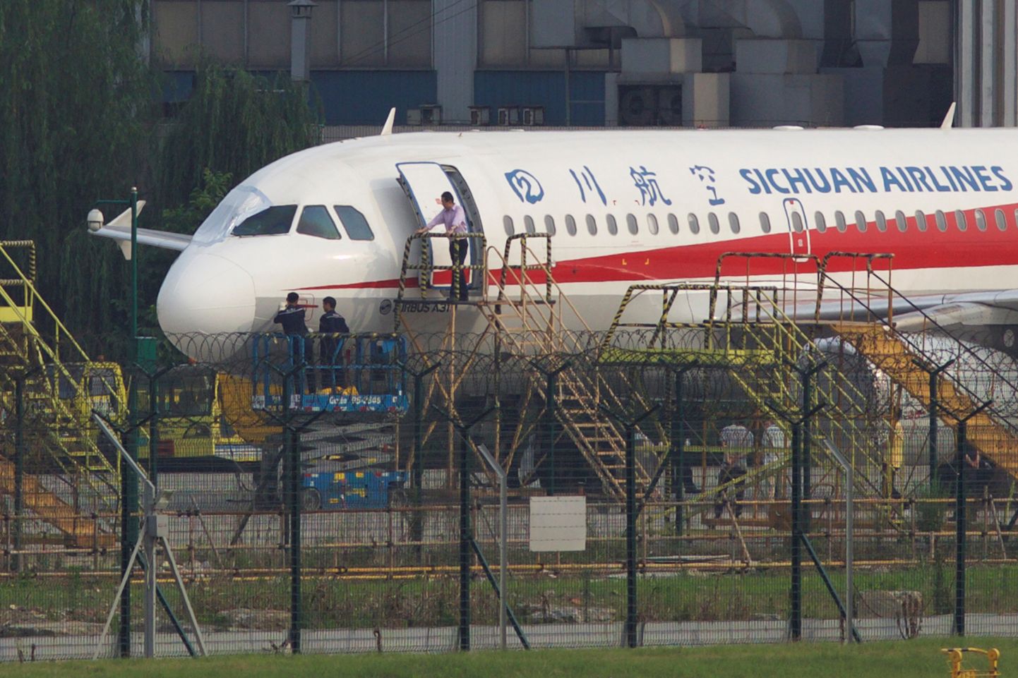 Работники аэропорта исследуют аварийный самолет после посадки в Ченгду.