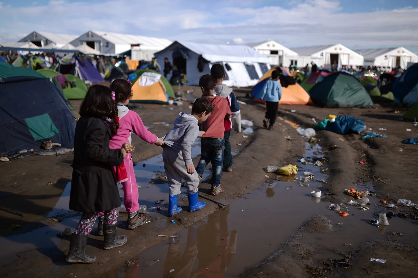 TOPSHOT - Children walk along a puddle at a makeshift camp after night's rainfall near the Greek village of Idomeni at the Greek-Macedonian border, on March 4, 2016, where thousands of migrants and refugees are stranded.
As the diplomatic efforts went into high gear ahead of a March 7 summit between the EU and Turkey, the human misery along the Greek-Macedonia border worsened after a night of driving rain and plummeting temperatures. The humanitarian crisis is particularly acute at the Idomeni crossing where around 12,000 people are stranded after Austria and the Balkan states imposed a cap on entries, triggering a rapidly-growing buildup in Greece.
 / AFP / LOUISA GOULIAMAKI