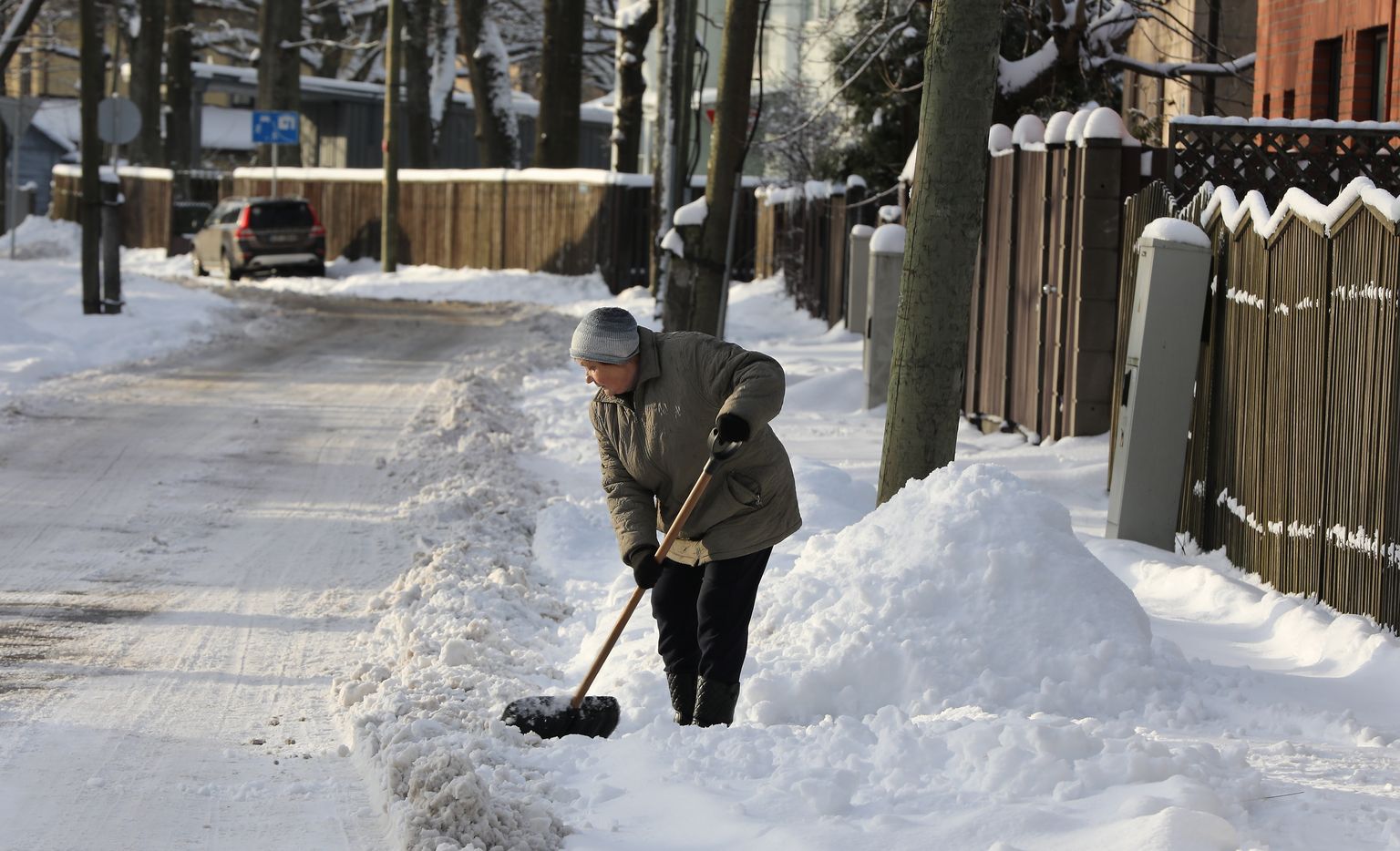 Sieviete tīra sniegu Zalves ielā.