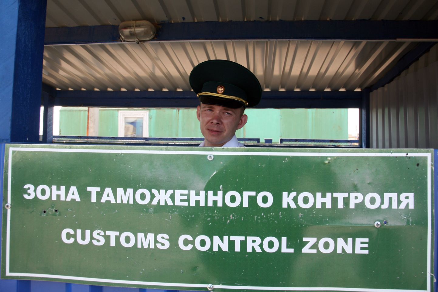 Российский таможенник смотрит из-за знака зоны таможенного контроля на российско-казахстанском погранпереходе в Караузеке незадолго до демонтажа таможенных постов вдоль 7560-километровой границы между двумя странами, 1 июля 2011 года.