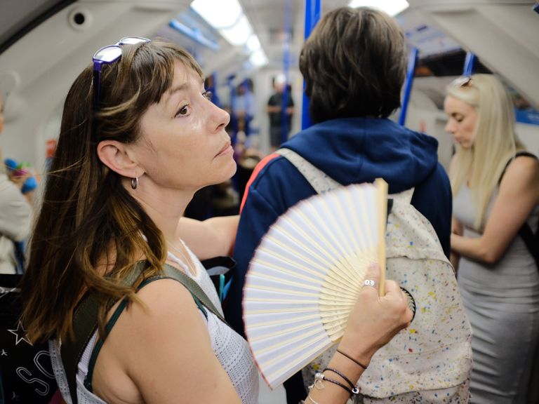 Naine jahutamas ennast lehvikuga Londoni metroos.