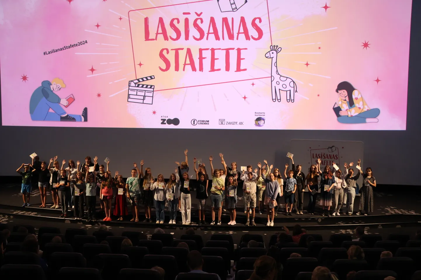 "Lasīšanas stafetes 2024" laureāti uz kinoteātra "Forum Cinemas" auditorijas skatuves.