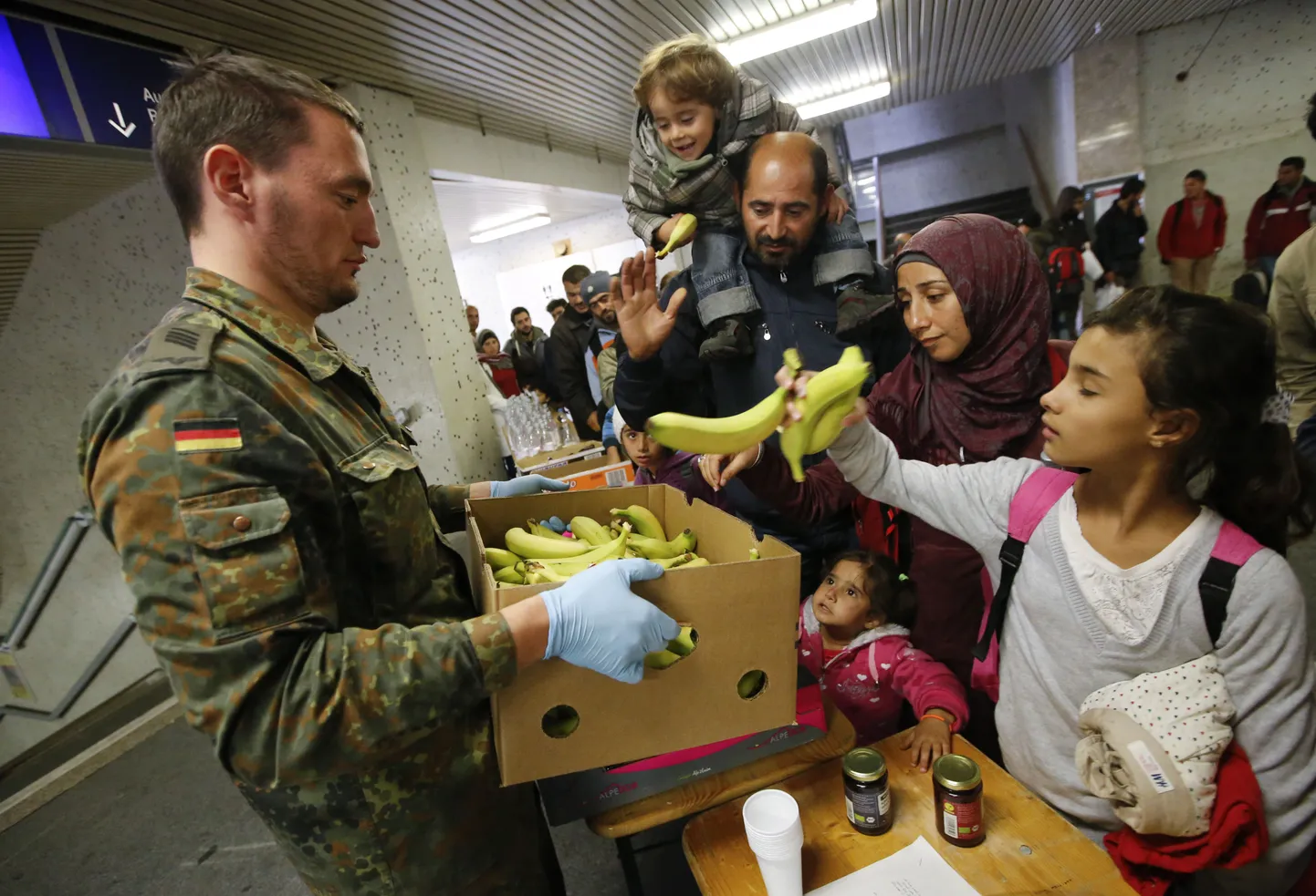 Bundeswehri sõdur jagamas põgenikele toitu enne nende põgenikelaagrisse transportimist.