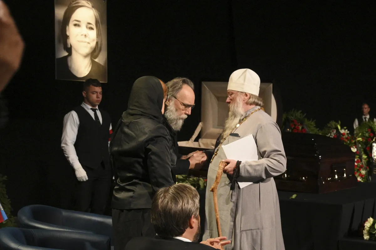 Aleksandr Dugin, centre, speaks with a priest during the final farewell ceremony for his daughter Daria Dugina in Moscow, Russia, Tuesday, Aug. 23, 2022.