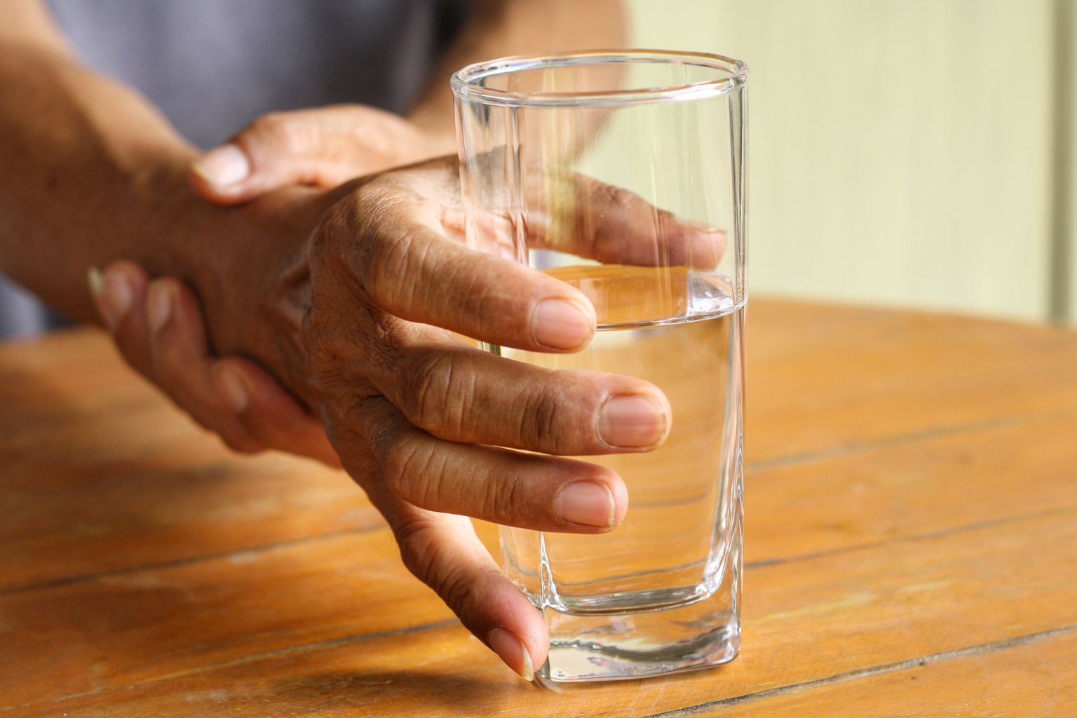 Parkinsoni tõvega mees joogiklaasi tõstmisel värisevat kätt toetamas.