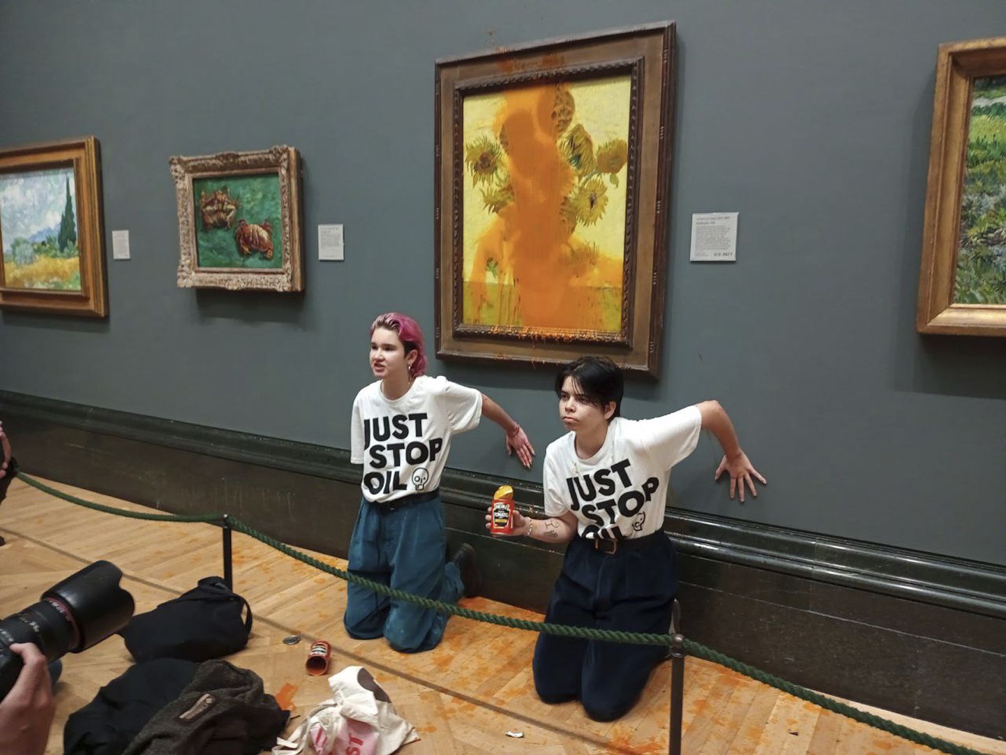 Aktīvistu grupas "Just Stop Oil" izdotā izdales fotogrāfija, kurā redzamas divas protestētājas, kuras Londonas Nacionālajā galerijā apmētājušas Vincenta van Goga slaveno 1888. gada darbu "Saulespuķes".