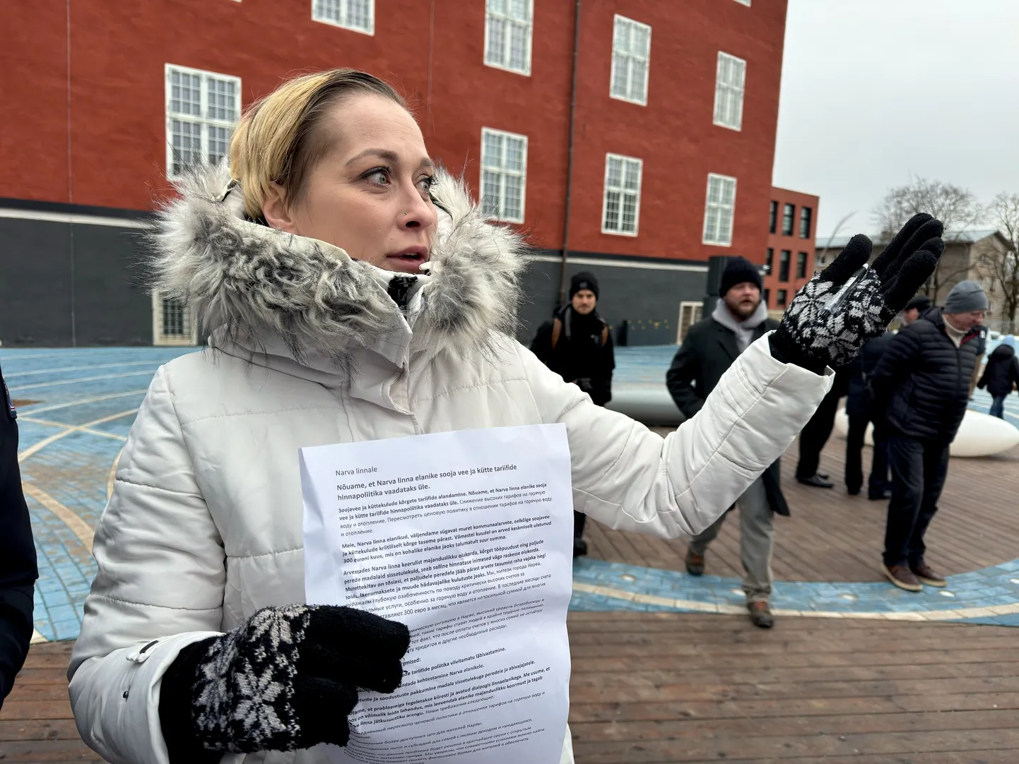 Нарвитянка Татьяна Алексеева держит в руке петицию, в основе которой недовольство жителей Нарвы из-за резко подорожавшего теплоснабжения. Фотография сделана на митинге, организованном и проведенном партией "KOOS" 1 февраля 2025 года у стен Нарвской ратуши.