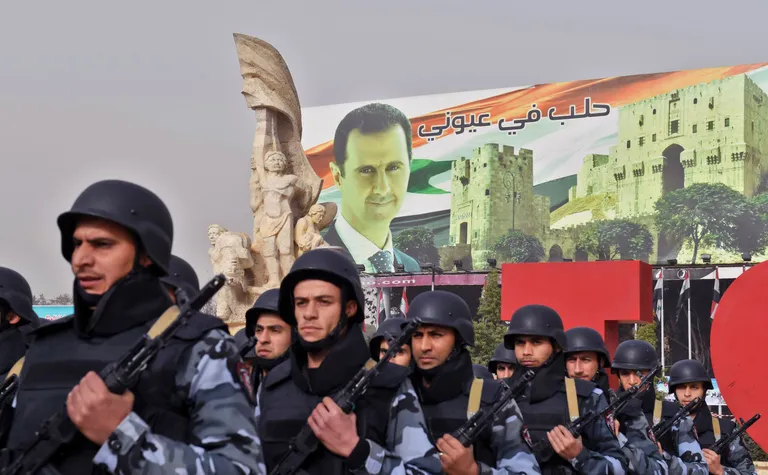 Süüria sõdurid marsivad mööda president Bashar al-Assadi plakatist.