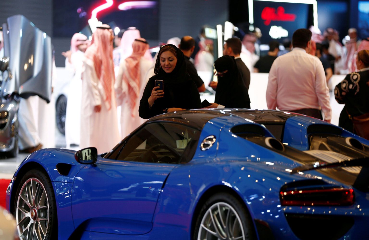 Saudi Araabia naine pildistab autonäitusel sõidukit.