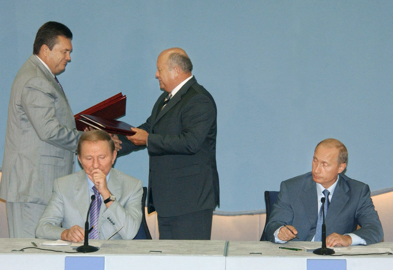 Главы правительств России и Украины Михаил Фрадков и Виктор Янукович (на втором плане справа налево) в присутствии президентов России и Украины Владимира Путина и Леонида Кучмы подписывают межправительственные соглашения. Сочи, 18 августа 2004 года.