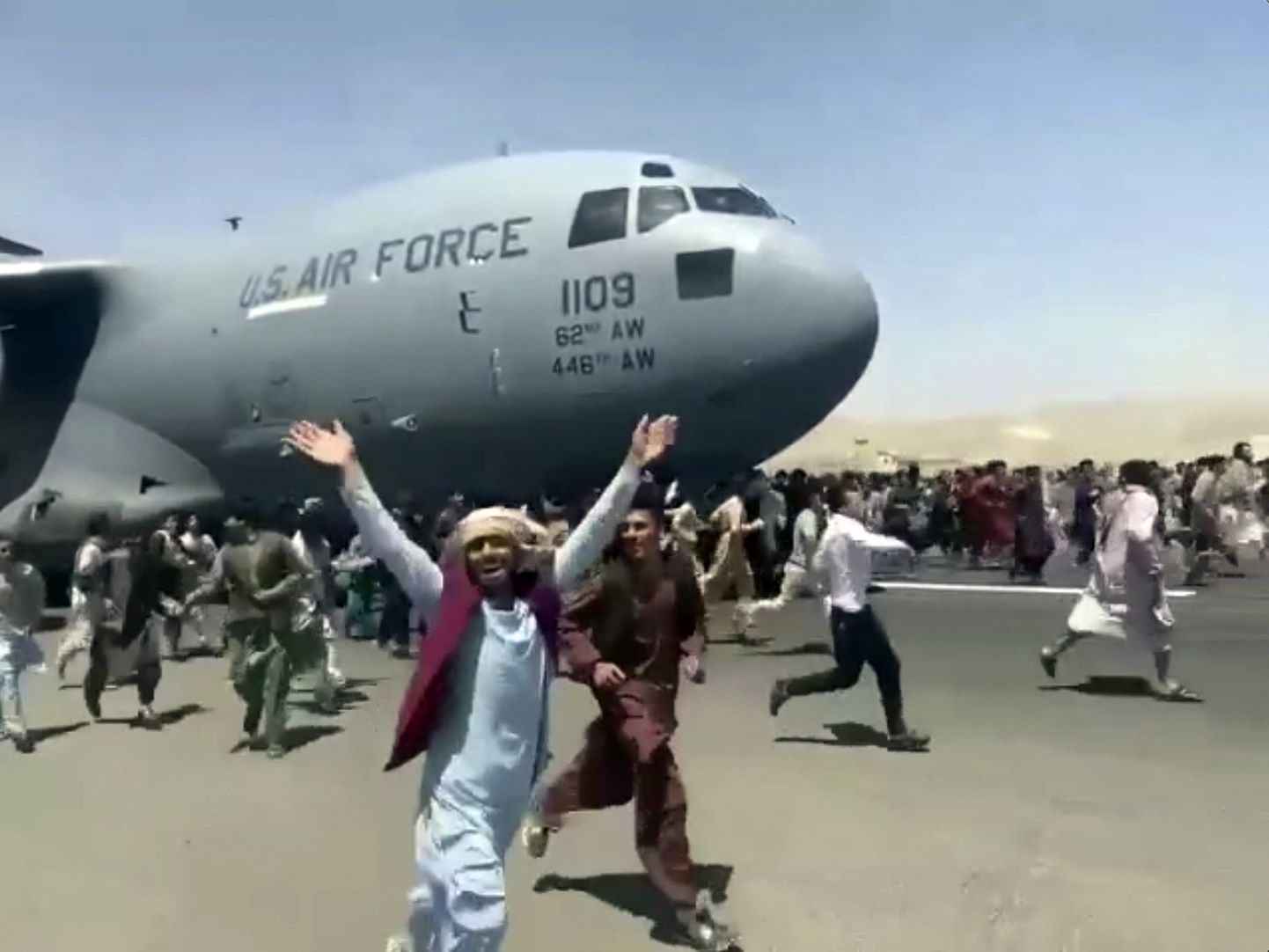 Жители Афганистана на взлетной полосе аэропорта в Кабуле пытаются покинуть страну после решения о выводе американских войск, август 2021 года.