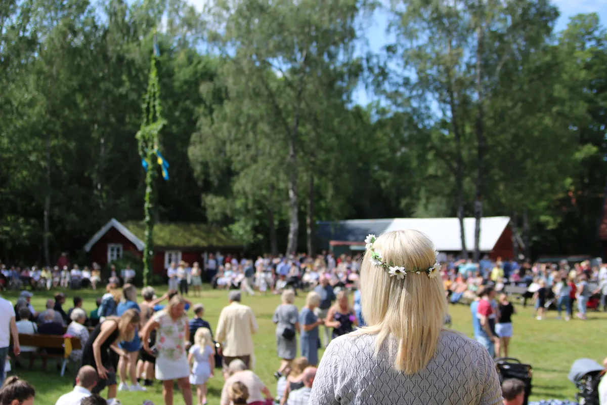 Midsommar. Taamalt paistab maypole ehk maipost, mille ümber tantsitakse ja lauldakse.