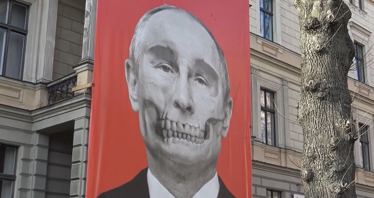 По мнению Сергея Алексашенко,политика Путина - это политика устрашения и поднятия ставок. На фото плакат напротив здания посольства РФ в Риге.
